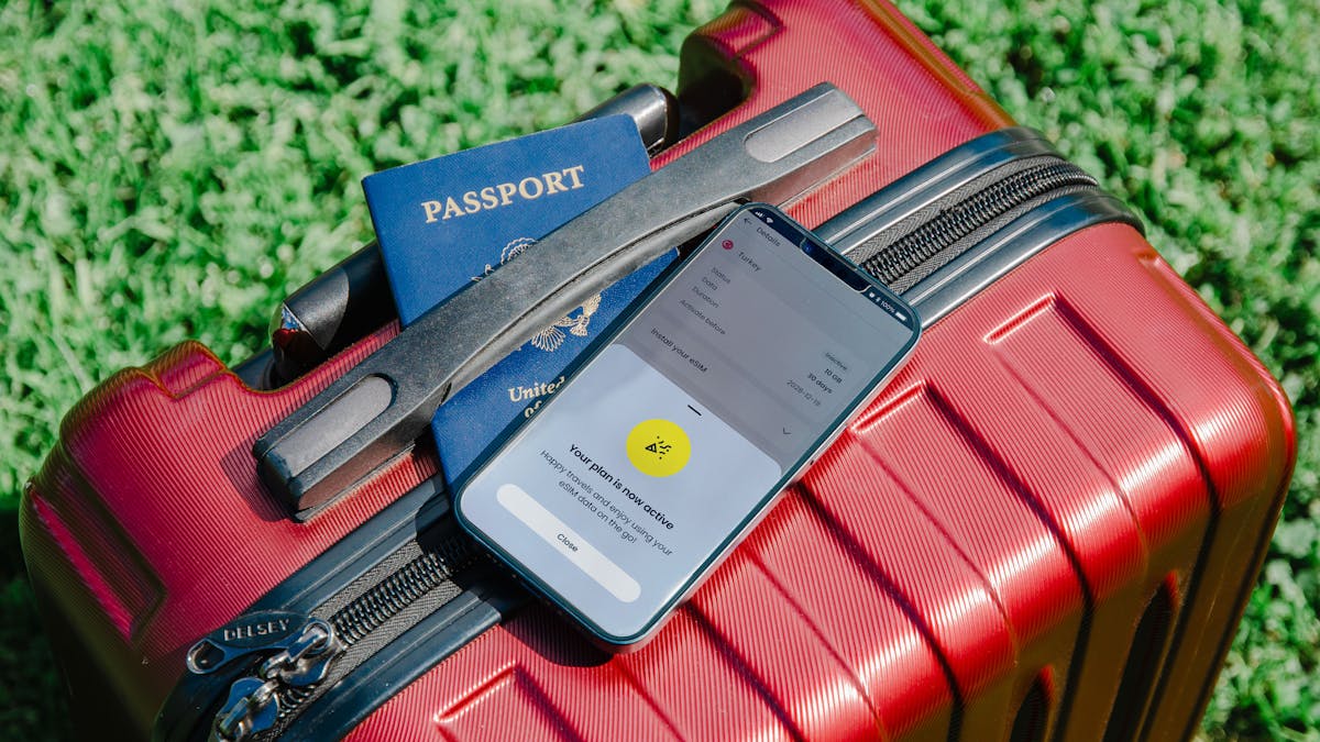 Traveler using a smartphone with passport and boarding pass on a wooden desk
