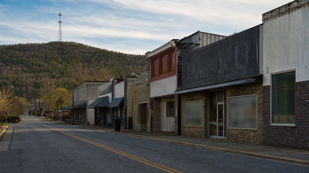 A quiet small-town main street near a hillside, illustrating a regional wireless shutdown