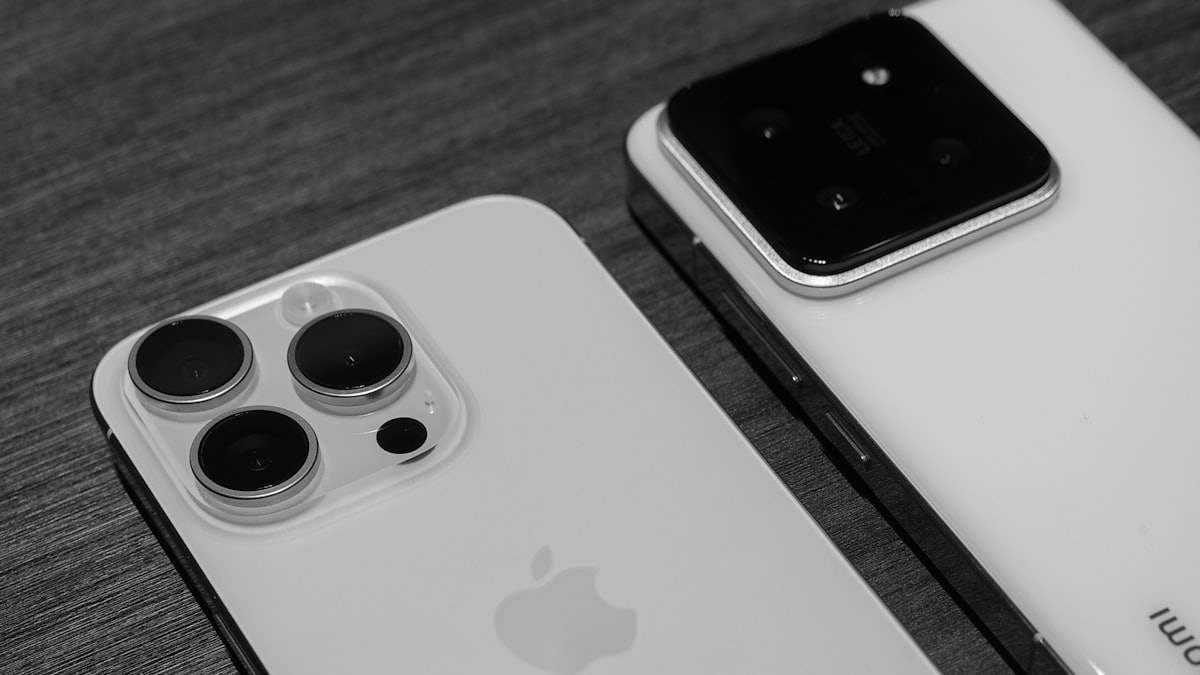 Two smartphones on a wooden table compared side by side